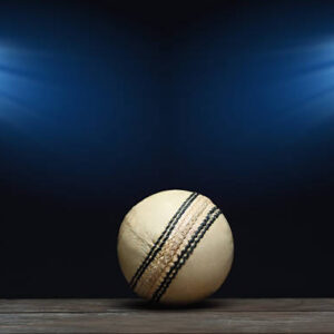 White Cricket Ball on wooden surface with stadium light